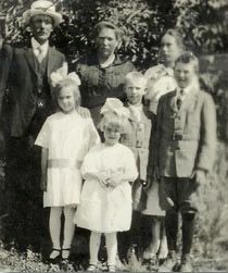 The August Dahlin family posed outdoors, with two adults and several children, the youngest girls in white dresses