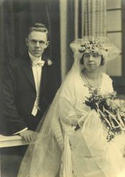 Arthur Tissell and Helen Clasen on their wedding day, he in a dark suit and bow tie, she in a veil with a flowered headpiece and bouquet