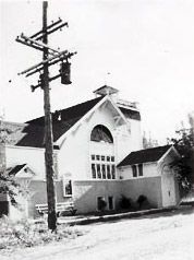 The original church building after one of its remodels, with an arched window in the gable and a lower wing on the right