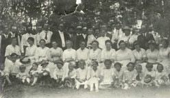 A large group of adults and children, many dressed in white, posed outdoors at a church gathering around 1929